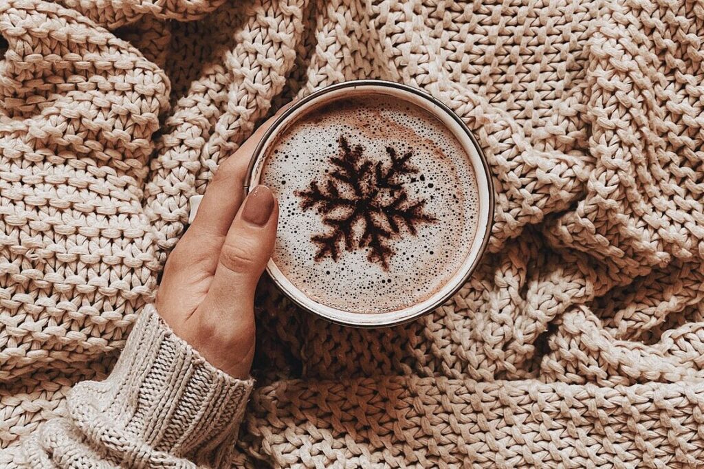 Main tenant une tasse de café décoré avec un pochoir à café en forme d'étoile des neige