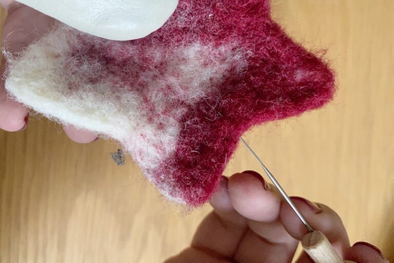 Rectifier la forme d'un objet en laine feutrée avec une aiguille.