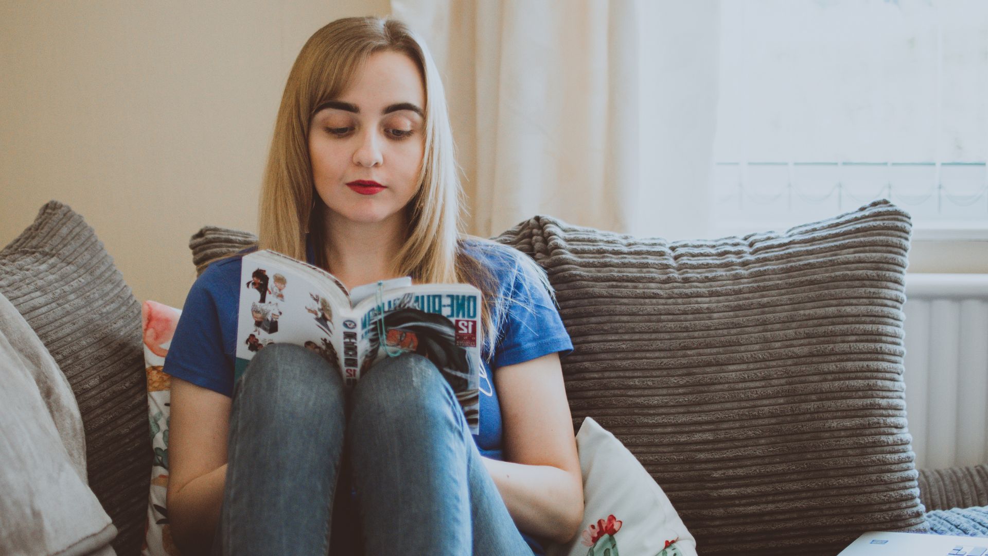 Jeune femme en train de lire un manga dans son canapé
