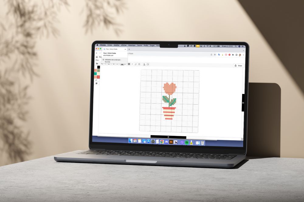 Personne utilisant Stitch Fiddle sur un ordinateur pour créer une grille point de croix gratuite.